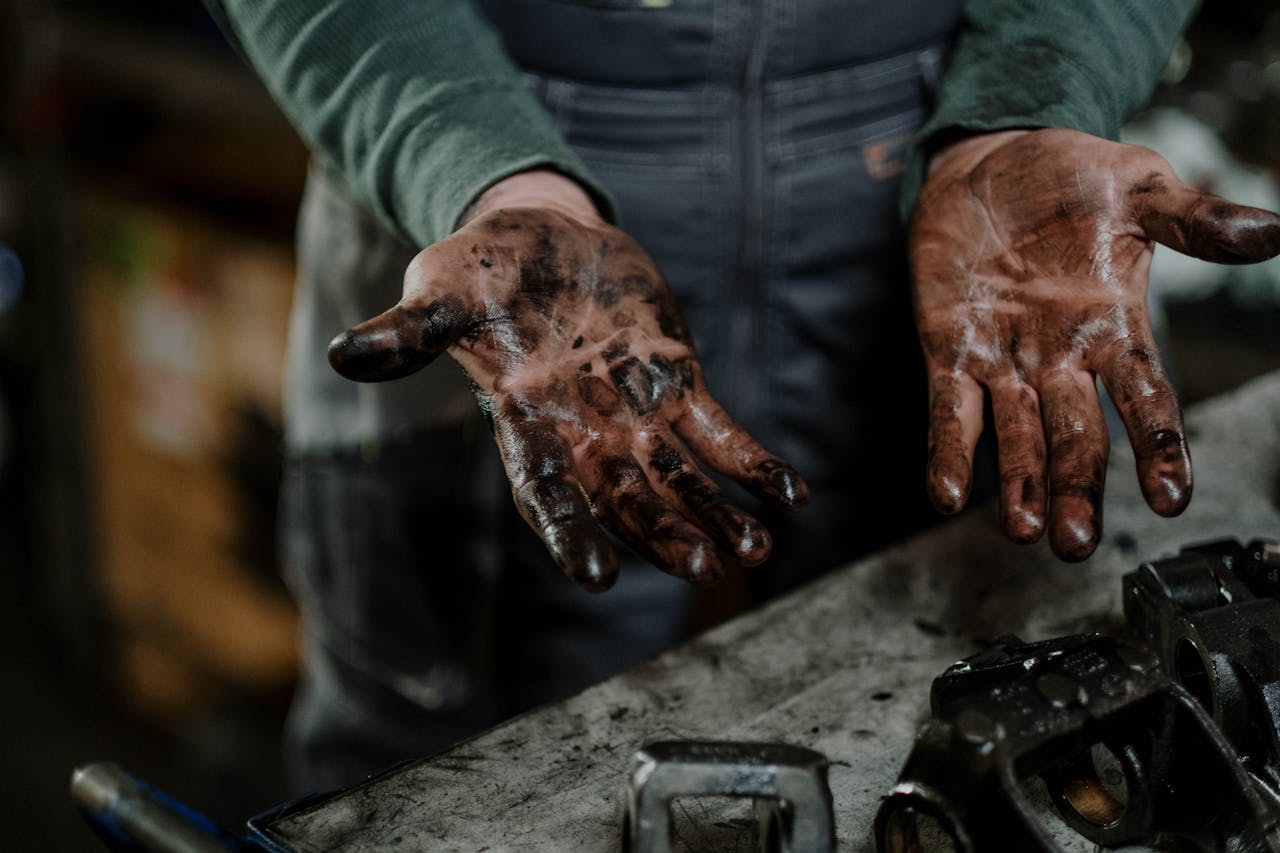hands stained with oil after handling car parts